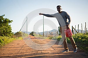 Man with petrol can hitchhiking at countryside