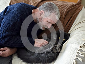 Man petting Persian cat on the sofa at home.