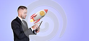 Man with phone and bitcoin rocket