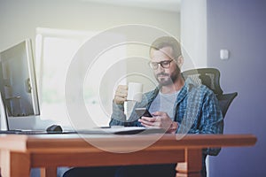 Man with phone and cup of coffee at office