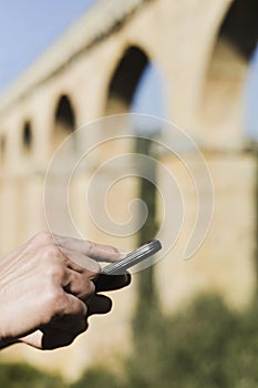 Man with phone at the roman aqueduct of Tarragona