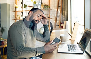 Man, phone and stress in coffee shop for remote work, job search or bad news of financial fail, debt or loan. African