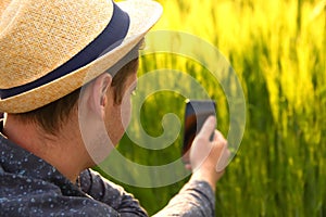 Man with phone on sunset. Young farmer working in a wheat field, inspecting and tuning irrigation center pivot sprinkler