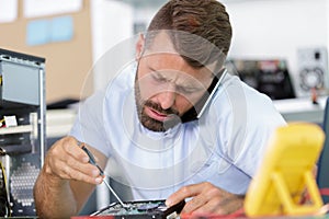 man on phone trying to fix pc