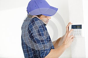 man on phone works on temperature thermostat