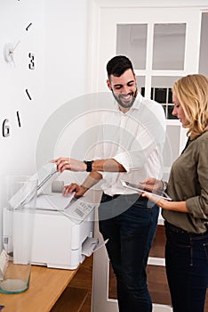 Man at a photo copier and woman holding tablet pc