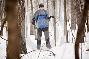 Man with photocamera in forest during snowfall on photo