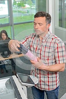 Man at photocopier holding package