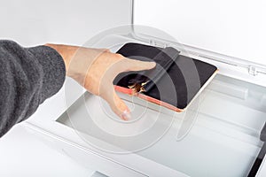 Man photocopying, scanning an old book on an open photocopier home printer Top view, hand placing a small book spread on copier