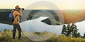 Man photographer with backpack and camera taking photo of sunset mountains.