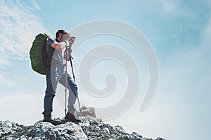 Man photographer with big backpack and camera taking photo of mountains