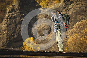 Man photographer with big backpack and camera taking photo of sunset mountains.