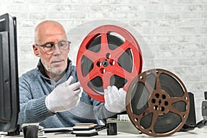 Man photographer looking at reel 16mm film