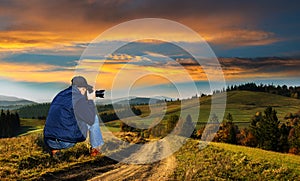 Man photographer in the mountains at sunset