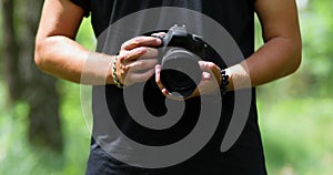 Man photographer with a photo camera configures outdoor