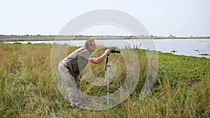 Man Photographer Takes Pictures On Camera Stand On Tripod In Wildlife Of Africa