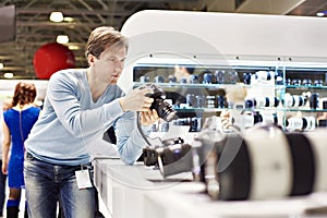 Man photographer tests digital SLR camera in shop