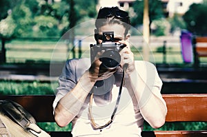 Man photographer. Young traveller or photographer sits on bench near backpack.