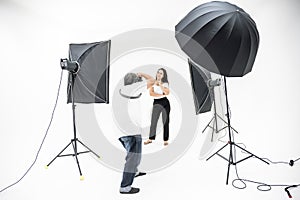 A man photographers are shooting pretty women in the studio with lighting equipment,