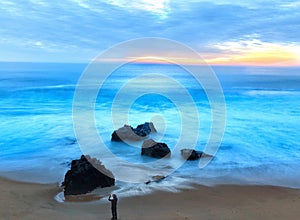 Man Photographing Crashing Waves at Sunset with Mobile Phone