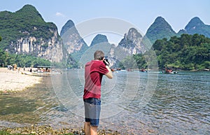 Man photographing scenery of the Li river in Yangshuo China