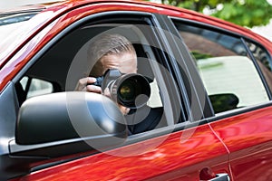 Man photographing with slr camera from car