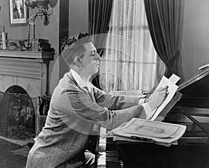 Man at piano writing on sheet music