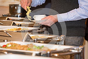Man picking food from chafing dish heaters