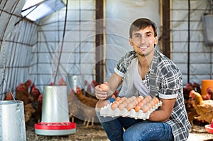 Man picking fresh eggs in chicken house