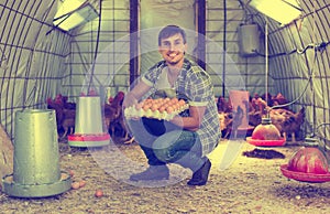 Man picking fresh eggs in chicken house