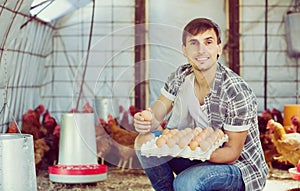 Man picking fresh eggs in chicken house