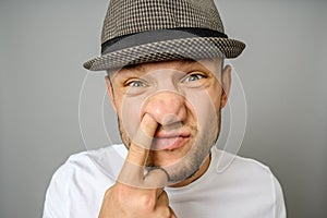 Man picking his nose on gray background