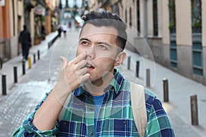 Man picking his nose outdoors photo