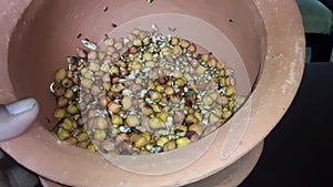 A man picking sprouted gram in an earthen pot.Sprouted Chana Moong Dal Almonds