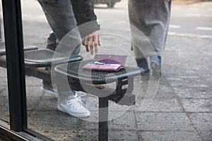 Man Picking Up A Lost Purse On Bench