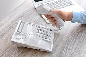 Man picking up telephone at table