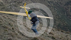 A man picks up his plane and climbs the hill