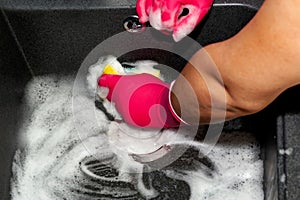 Man pink gloves washes sink.
