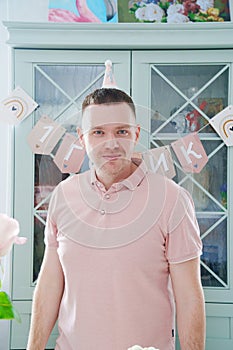 A man in a pink polo shirt at the closet against the background of a cabinet