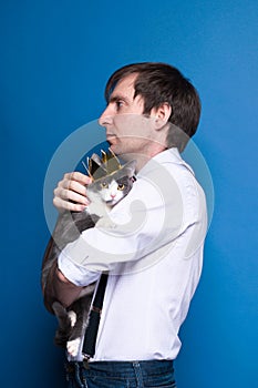 Man in pink shirt and black suspenders holding grey cat in golden homemade crown