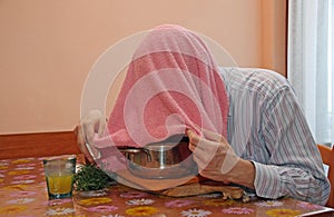 Man with pink towel breathe balsam vapors to treat colds and flu photo