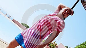 Man in pink tunics posing look in camera at beach umbrella. Wind. Summer sunny day. Blue sky