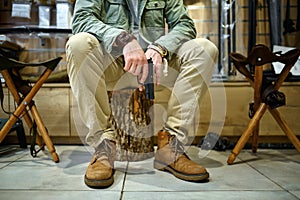 Man with pistol sitting on stump in gun store