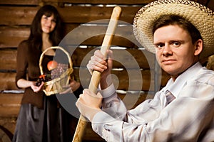 Man with pitchfork and in hat, woman with basket