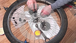 A man places ball bearings in a greased hub on a bicycle rear wheel. Lowers the axle into the bushing. Do-it-yourself mountain