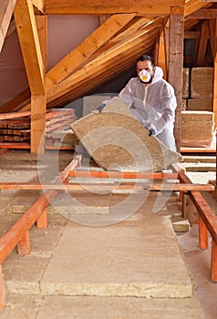 Man places rockwool thermal insulation between wooden scaffolding