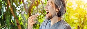 Man placing a bite plate in his mouth to protect his teeth at night from grinding caused by bruxism BANNER, LONG FORMAT