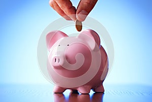 Man placing a coin into a piggy bank