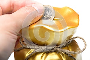 Man placing a euro coin into a piggy bank