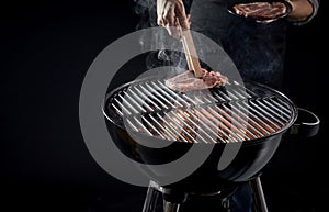 Man placing raw meat onto a hot barbecue